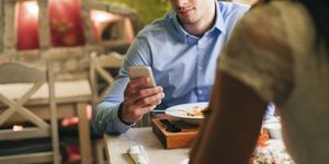 man checking messages while having dinner in a restaurant