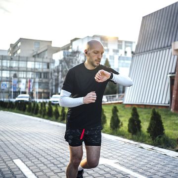 man checks data on a fitness tracker while running