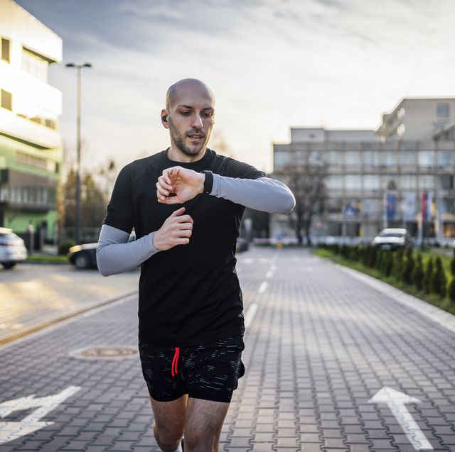 man checks data on a fitness tracker while running