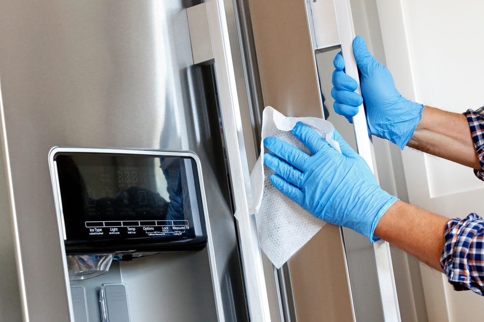 man cleaning refrigerator with disinfectant wipe