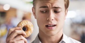 Man contemplating biting a sugar coated donut