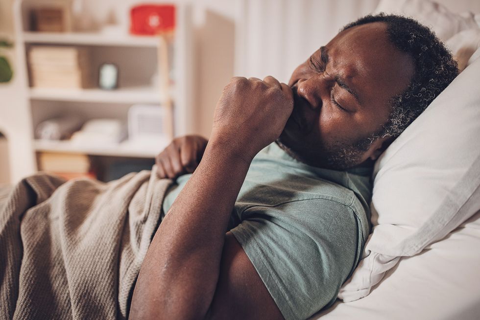 man coughing in hospital bed