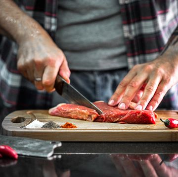 man cuts beef meat in the kitchen