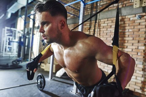 Man doing exercise with suspension straps in gym