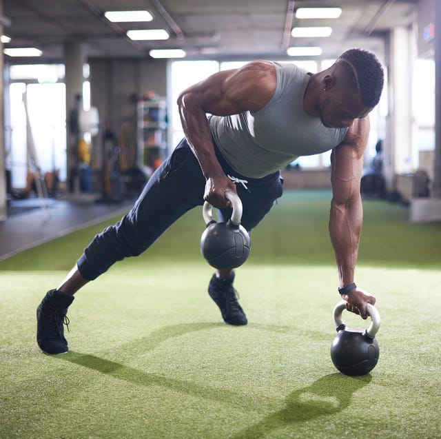 man doing plank with kettlebells in gym