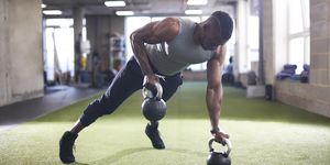 man doing plank with kettlebells in gym