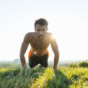 man doing pushups on a meadow