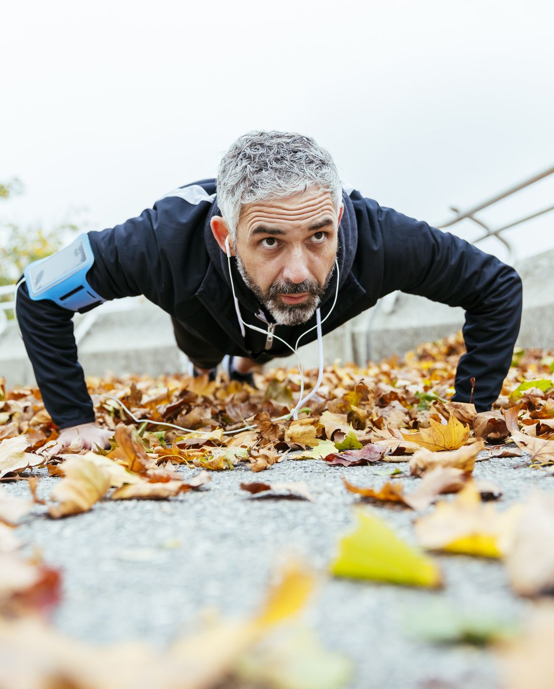 Man doing pushups surrounded by autumn leaves