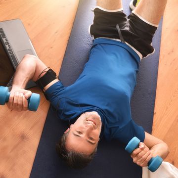 man doing sports with dumbbells lying on mat top view