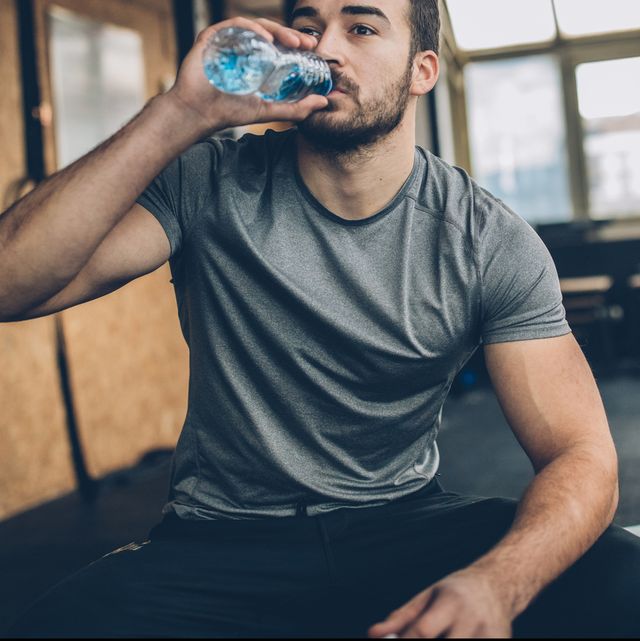 man drinking water after training in gym