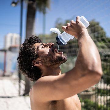 man drinking water in a beach volleyball court