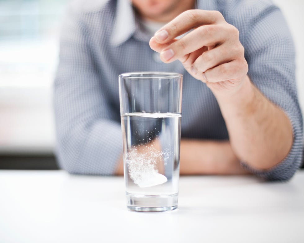 man dropping antacid into a glass of water