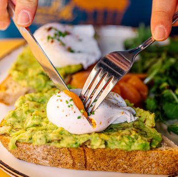 man eating avocado toast with poached egg and salmon, close up view