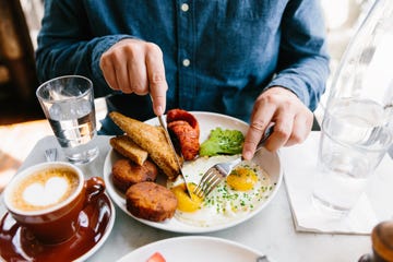 man eating breakfast with fried eggs, hash brown, avocado, sausage and toasted bread