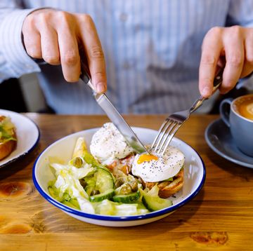 man eating breakfast with poached eggs, fresh salad and coffee