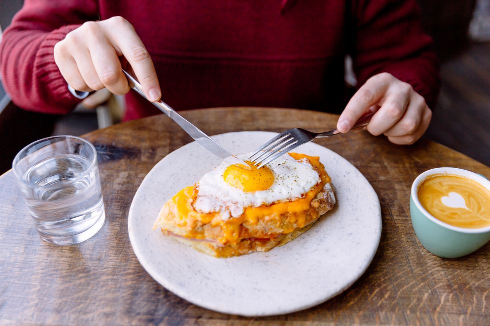 person having croque madame sandwich with cheese and fried egg