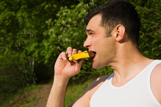 un hombre come una barrita energética tras hacer deporte