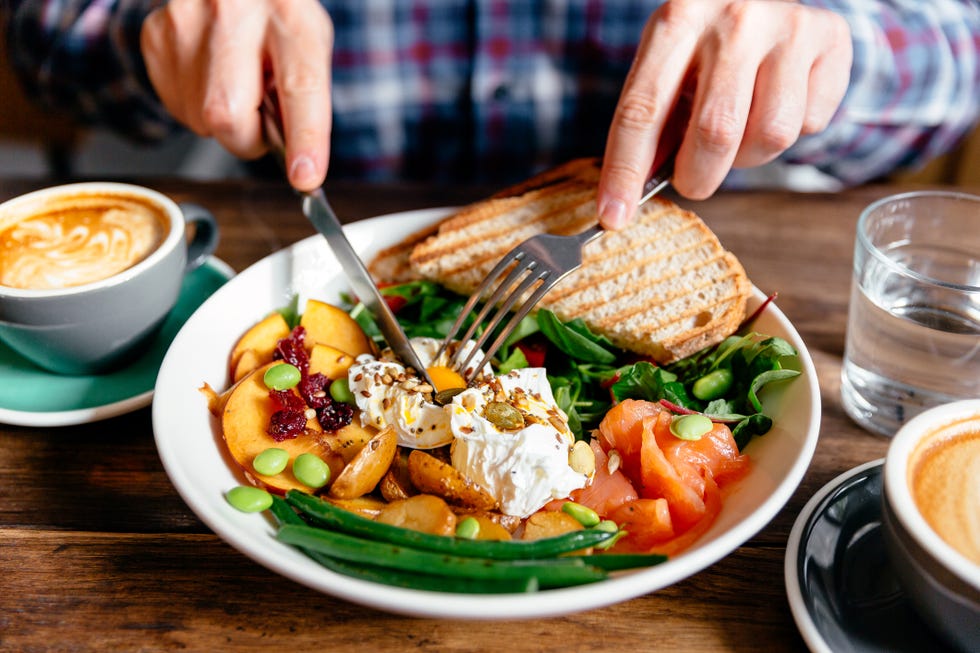 man eating healthy breakfast with poached egg, salmon, roasted potato, spinach