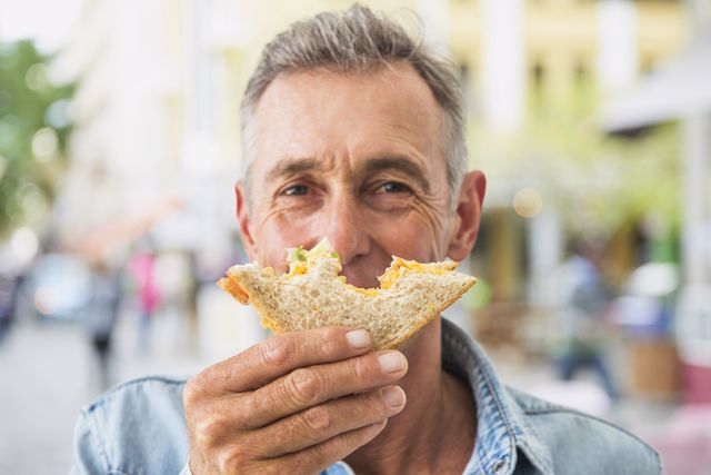 man enjoying a sandwich outdoors.