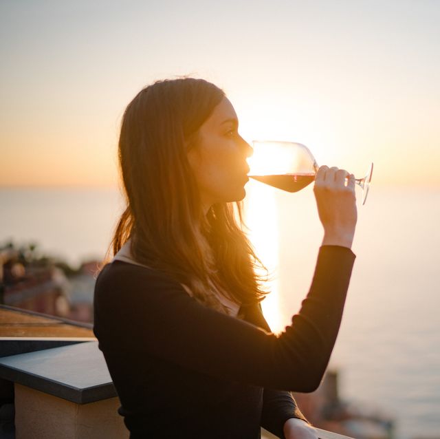 man enjoys red wine on terrace above old town and sea