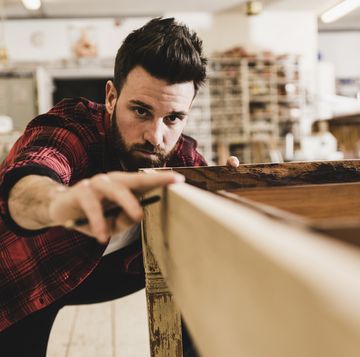 man examining wood in workshop
