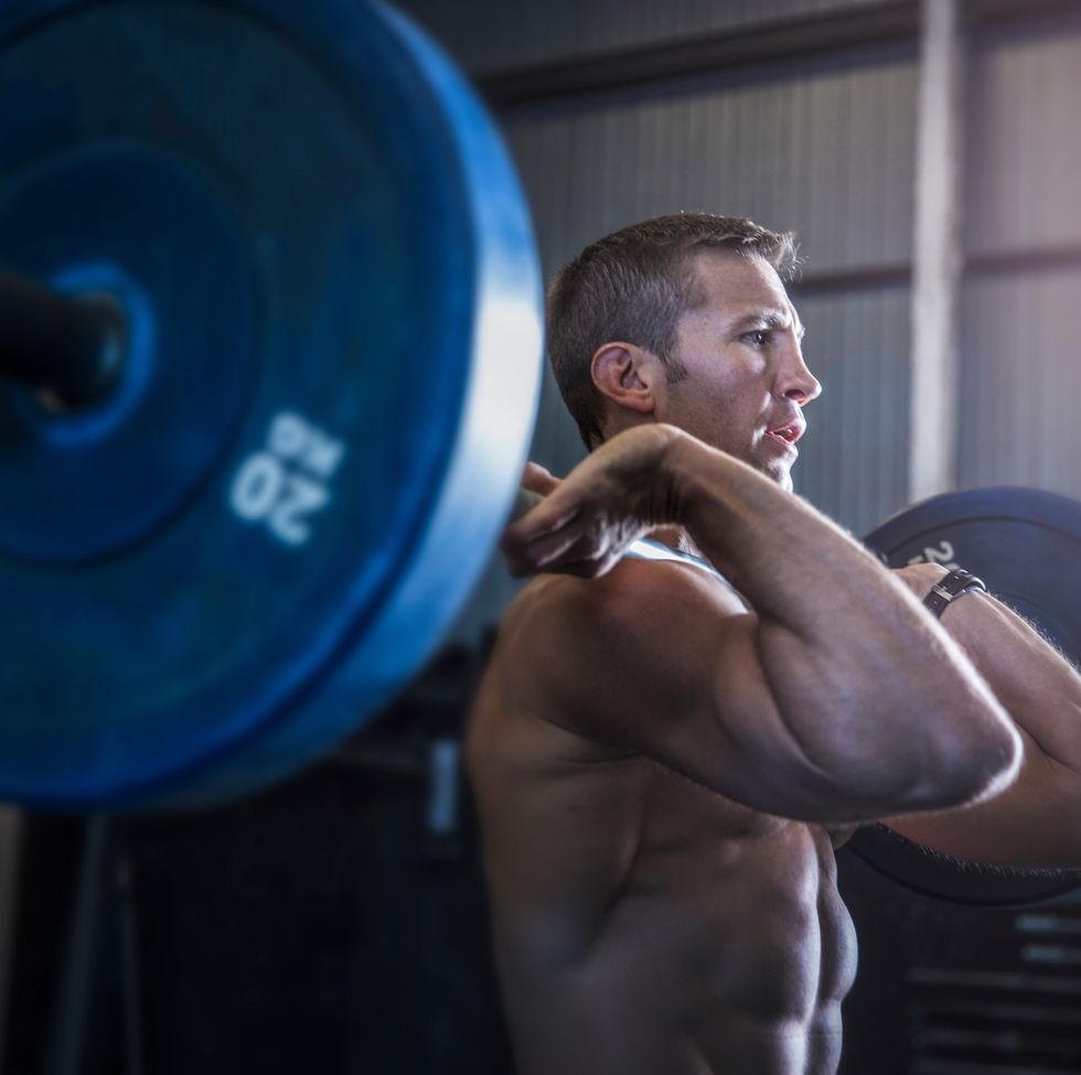 Man exercising in gym, using barbell, front squat position