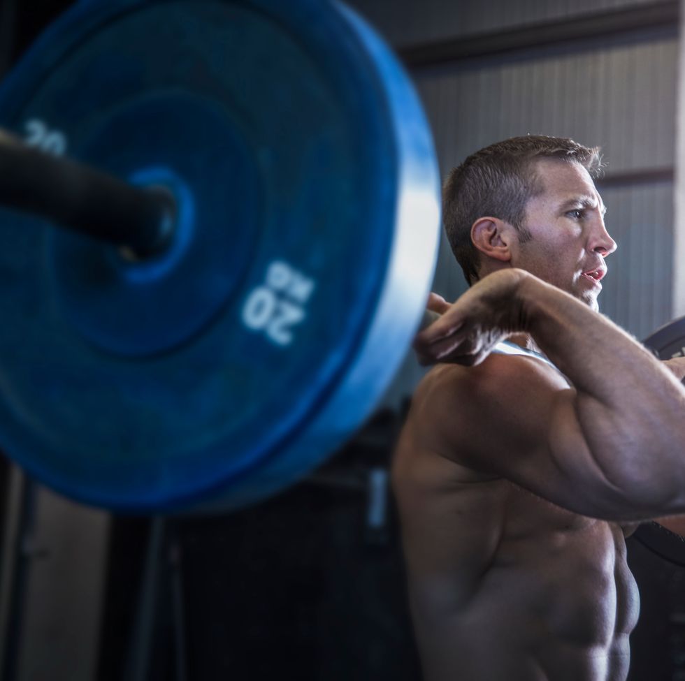 Man exercising in gym, using barbell, front squat position
