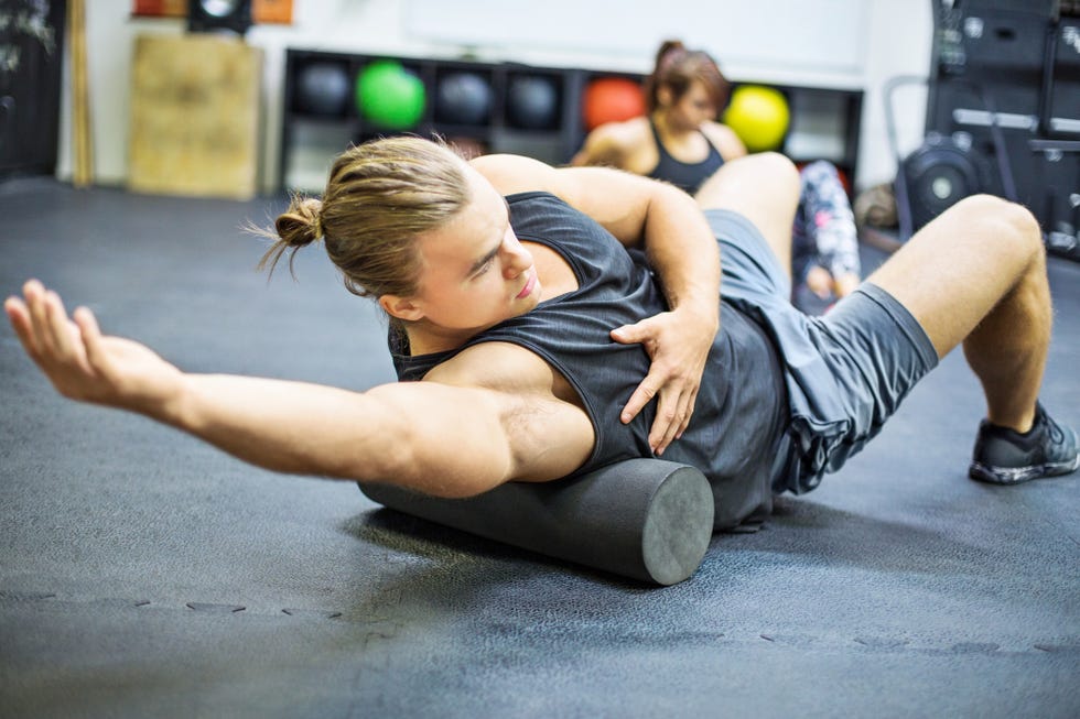 Man exercising on foam roller in gym