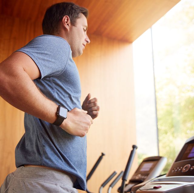man exercising on treadmill at home wearing smart watch
