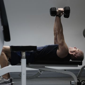 man exercising with dumbbells on weight bench