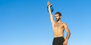 man exercising with kettlebell under blue sky