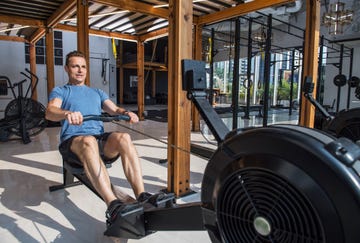 man exercising with rowing machine in gym