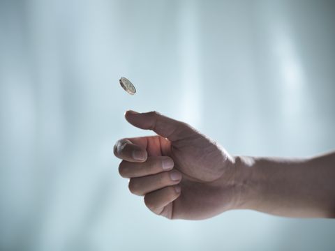 man flipping one pound coin, pounds sterling