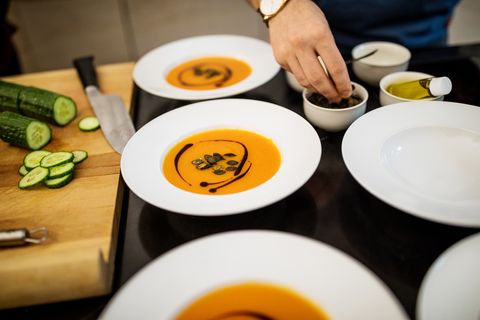 man garnishing squash soup with seeds during dinner party