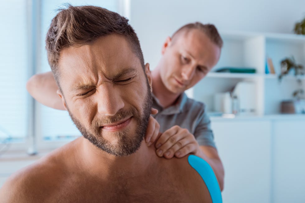 hombre con una mueca de dolor en el fisioterapeuta