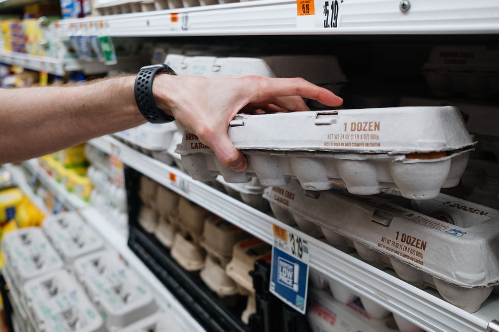 man grabs carton of eggs at supermarket