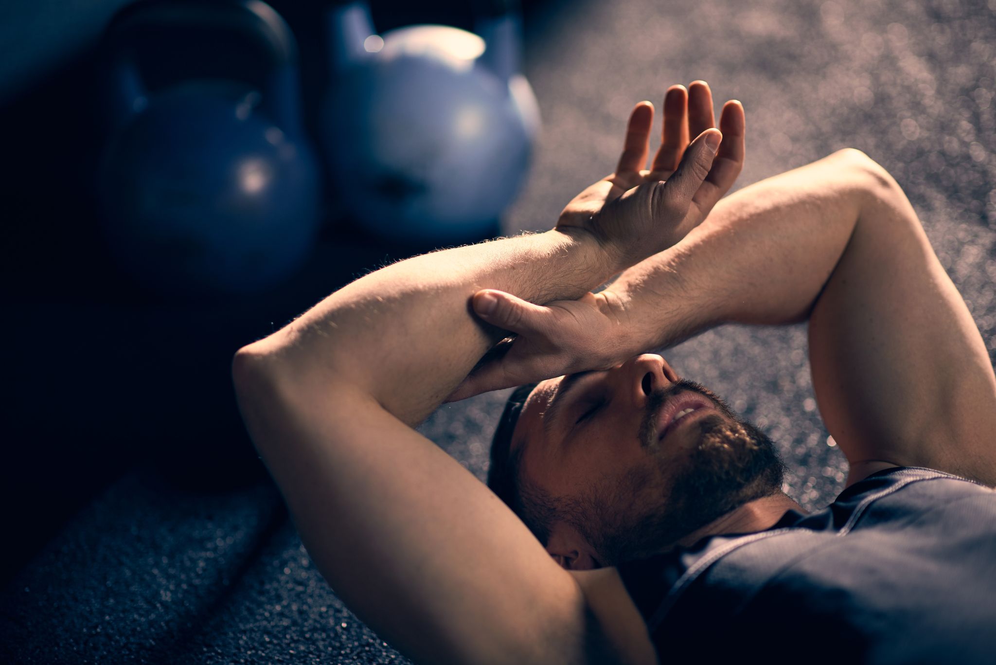tired athlete lying down with hand on his head at home