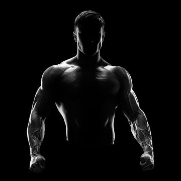 silhouette of a strong fighter confident young fitness man with strong hands and clenched fists dramatic light