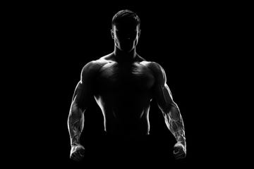 silhouette of a strong fighter confident young fitness man with strong hands and clenched fists dramatic light