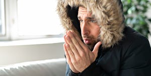 a man have cold on the sofa at home with winter coat