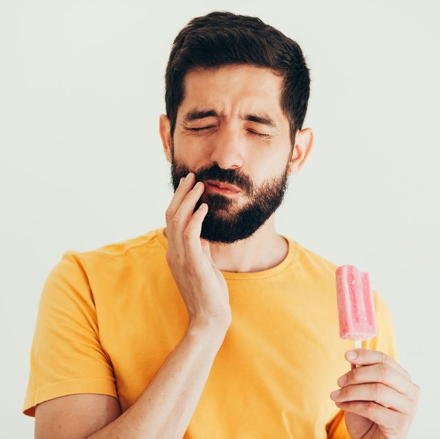 man have sensitive teeth with ice on white background