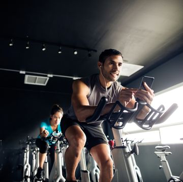 man holding his cellphone while exercising on a gym bike