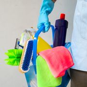 Man holding mop and plastic bucket with brushes, gloves and detergents in the kitchen