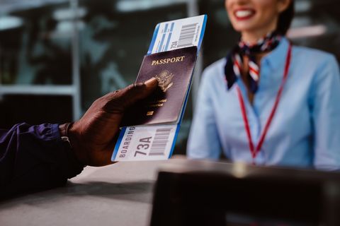 man holding passport and boarding pass at airline checkin counter