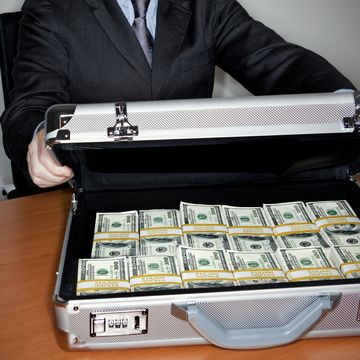 man holding silver briefcase full of $100 bills