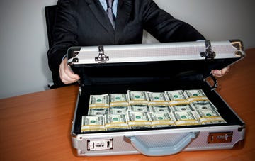 man holding silver briefcase full of $100 bills