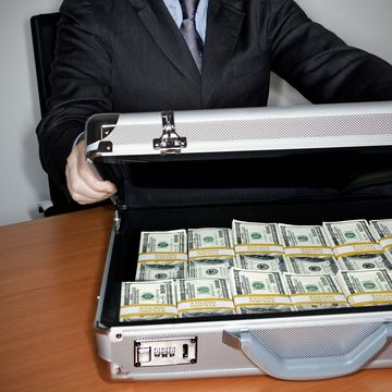 man holding silver briefcase full of $100 bills
