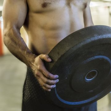 Man holding weight plate and exercising in gym