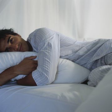 man hugging pillow in bed