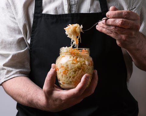 a man in an apron holding a fermented cabbage